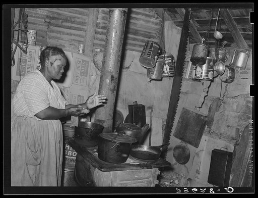 Negro farm owner working in kitchen. Arkansas River bottoms near Vian, Oklahoma