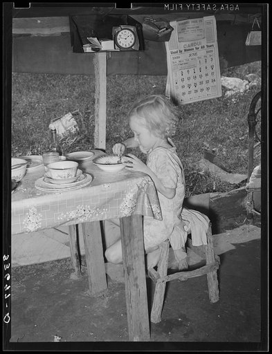 Daughter of day laborer eating lunch in tent home near Spiro, Oklahoma. Sequoyah County