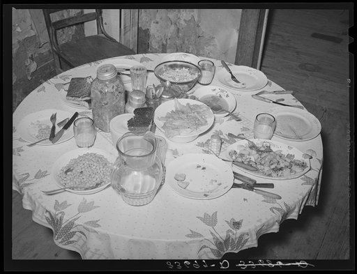 Dinner table of tenant farm family living near Sallisaw, Oklahoma. Food consists of beans, cornbread, lettuce, fried potatoes, fatback and gravy, cole slaw and sweet milk