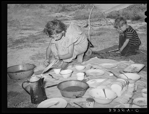 Migrant girl scraping plates after noonday meal along the highway near Muskogee, Oklahoma. Muskogee County