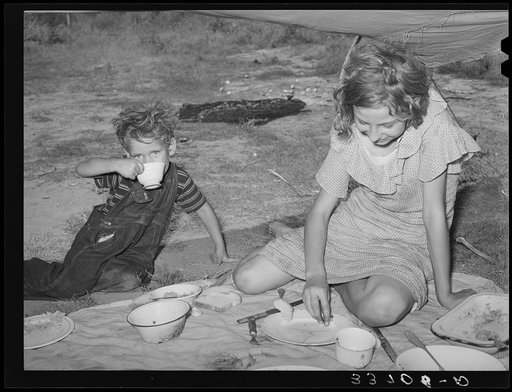 Migrant children eating under tarpaulin stretched from their automobile parked near Muskogee, Oklahoma. Muskogee County