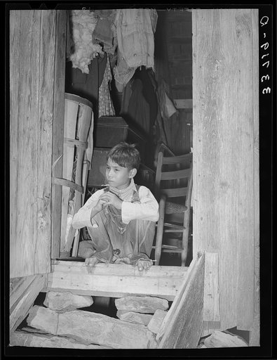 Indian child "hunkering down" in doorway of farm home near Sallisaw, Oklahoma. Hunkering down is an Indian slang term for this way of sitting on your heels