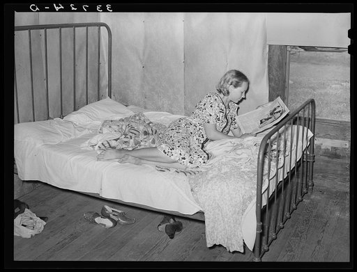 Daughter of woman tenant farmer reading magazine. Near Sallisaw, Oklahoma