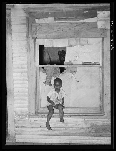 Son of Negro agricultural day laborer sitting in window of his home. Muskogee County, Oklahoma