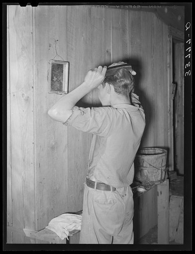 Migrant boy combing his hair at his home near Muskogee, Oklahoma