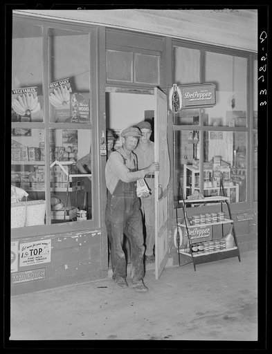 Migrant family emerging from grocery store where they have stopped along the road in order to buy bread and potatoes, which will form the basis for their noonday meal. Near Henryetta, Oklahoma