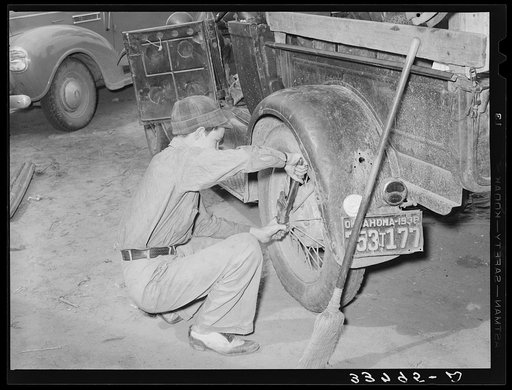 Tightening the rear wheel on truck which will carry migrant family to California from Muskogee, Oklahoma