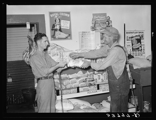 Head of migrant family buying loaf of bread in grocery store of small town near Henryetta, Oklahoma
