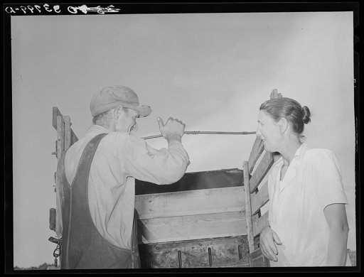 Migrant man and woman at rear of their truck before departure for California from Muskogee, Oklahoma