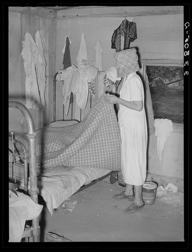 Removing bedclothing from house, preparatory to packing for departure to California from Muskogee, Oklahoma