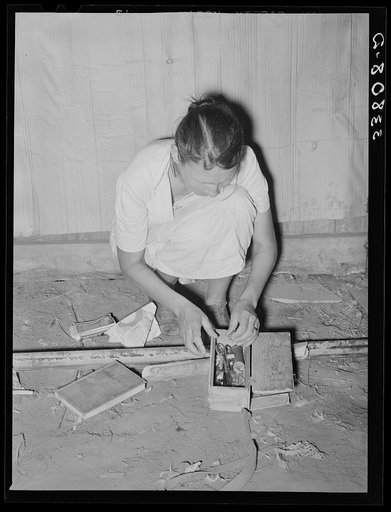 Packing the little odds and ends in small box, preparatory for leaving for California from Muskogee, Oklahoma