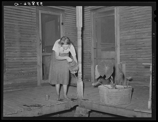 Front porch of tenant farmer's house near Muskogee, Oklahoma. Daughter is getting ready to change water in goldfish bowl. Refer to general caption number 20
