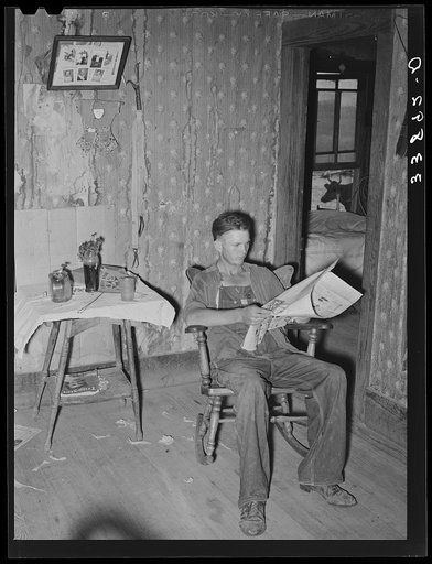 Son of tenant farmer reading the morning paper while waiting for noonday meal. Near Muskogee, Oklahoma. Refer general caption number 20