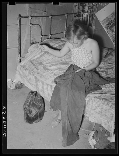 Young married girl living in Mays Avenue camp patching her husband's overalls. Oklahoma City, Oklahoma