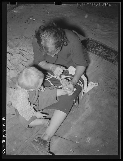 Mother of child pointing to his cut toe, injured while playing in trash and debris of camp. Mays Avenue camp, Oklahoma City, Oklahoma