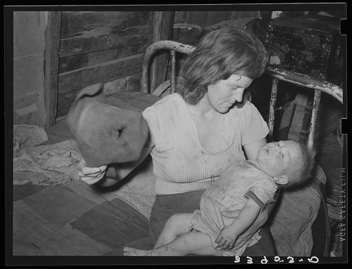 Mother fanning child with old hat to keep off flies. Mays Avenue camp, Oklahoma City, Oklahoma. See general caption 21