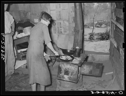 Woman preparing breakfast in shack home. Mays Avenue camp, Oklahoma City, Oklahoma