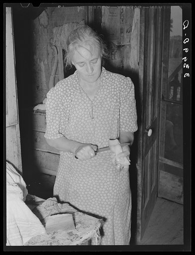 Wife of tenant farmer slicing fatback for noonday meal near Muskogee, Oklahoma. See general caption 20
