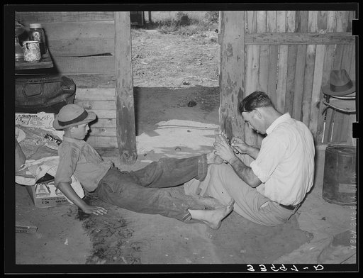 Resident of Mays Avenue camp, Oklahoma City, Oklahoma, taking piece of glass out of boy's foot. See general caption 21