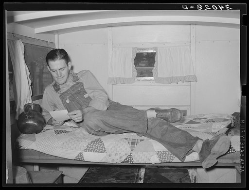 Oil field worker in his trailer home reading a letter. Seminole, Oklahoma
