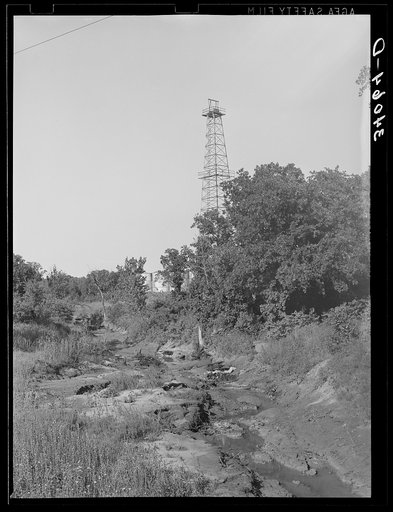 Oil derrick with waste oil in stream. Oklahoma City oil field, Oklahoma
