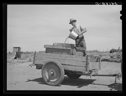 Filling a tank full of water to take to the school house. School was just about to open when this picture was taken in Baca County, Colorado