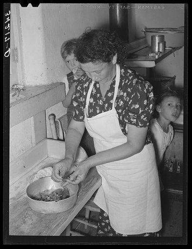 Spanish-American woman peeling peppers after the skins were loosened by heating on top of stove. Near Taos, New Mexico