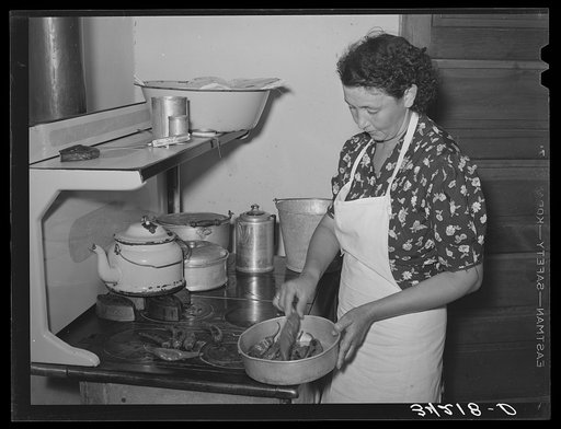 Spanish-American woman removing peppers from stove. Taos, New Mexico