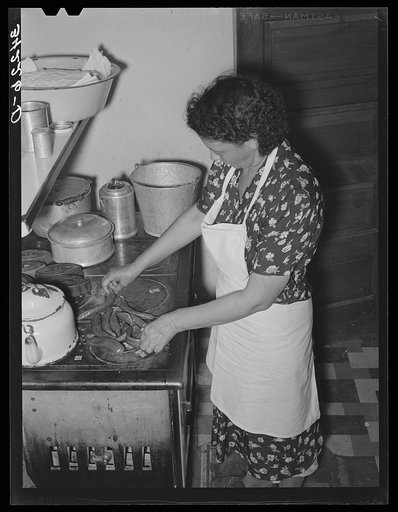 Spanish-American woman placing and turning peppers on the stove near Taos, New Mexico