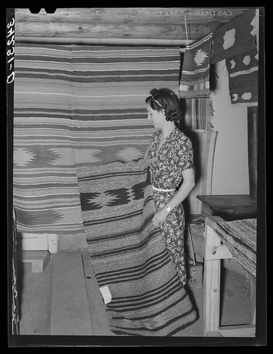 WPA (Works Progress Administration/Work Projects Administration) project supervisor displaying some of the articles made at her weaving project. Costilla, New Mexico