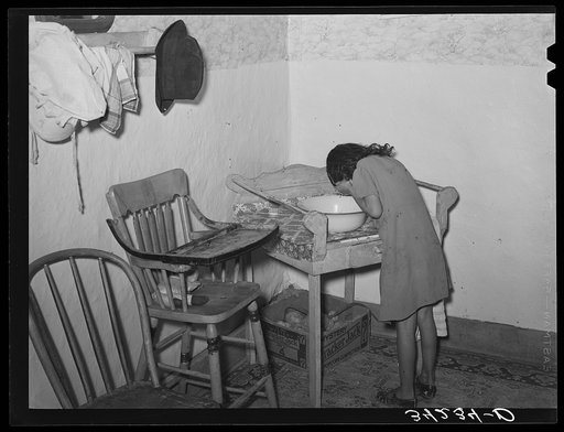 Spanish-American girl washing her face. Farm home near Taos, New Mexico