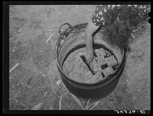 Spanish-American woman cutting soap which she made in this kettle. Near Taos, New Mexico