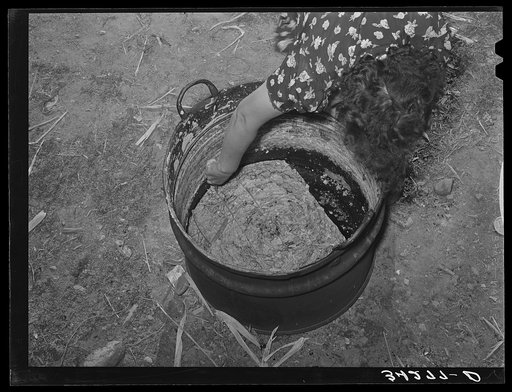 Untitled photo, possibly related to: Spanish-American woman cutting soap which she made in this kettle. Near Taos, New Mexico