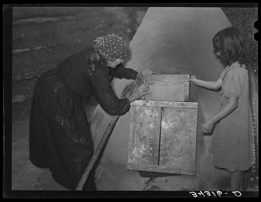 Covering entrance of outdoor earthen oven while bread is baking. Near Taos, New Mexico