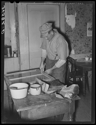 Farmer puttying window glass in his house in Orange County, Vermont