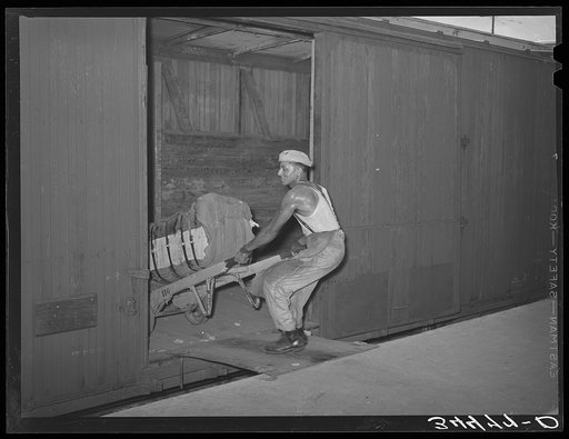 Negro unloading bale of cotton from railroad car. Compress, Houston, Texas
