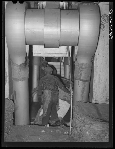 Adjusting the bale of cotton in the jaws of the compressor. Houston, Texas