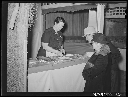 Farm couple watching the saleswoman demonstrate the use of a gadget at booth at the Gonzales Country Fair, Texas