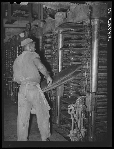 Removing the cotton seed cake and mat from hydraulic presses after the oil has been removed. Cotton seed oil mill, McLennan County, Texas