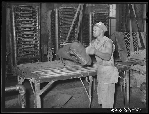 Workman removing cotton seed cake from mat after oil has been removed. The cake is removed by means of a mandrel machine. Cotton seed oil mill, McLennan County, Texas. The movement of this machine was so fast that it was impossible to stop the action with fastest shutter speed of the camera