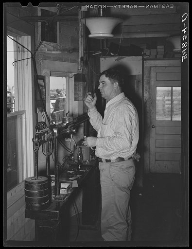 Man in office at stockyards. After cattle are sold at auction he calls out to the keepers in the pens to put cattle with certain numbers in certain pens. In this way each buyer's cattle are separated and delivery is facilitated. Stockyards, San Angelo, Texas