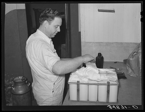 Scraping surplus ice cream mix from filled cartons with a spatula. Creamery, San Angelo, Texas