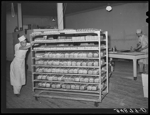 Pushing truckload of freshly baked bread and rolls at bakery. San Angelo, Texas