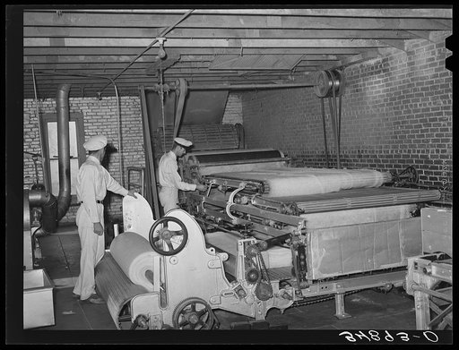 Formation of cotton bat for stuffing mattresses. Mattress factory. San Angelo, Texas. This bat is usually made from cotton linters which is that part of the cotton closest to the seed. Dark in color and short of staple