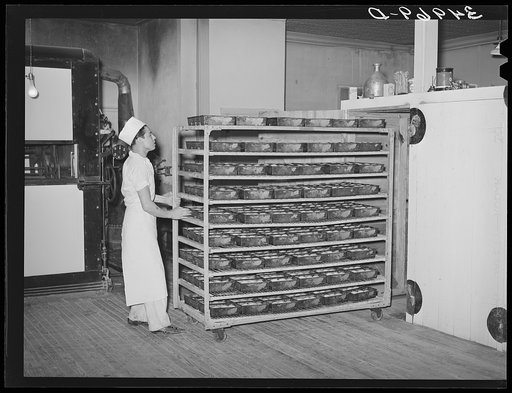 Moving trayload of bread and rolls into the rising compartment, which has regulated temperatures. Bakery, San Angelo, Texas
