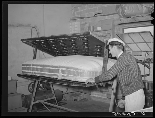 Getting ready to tuft a mattress in clamping machine. Mattress factory, San Angelo, Texas