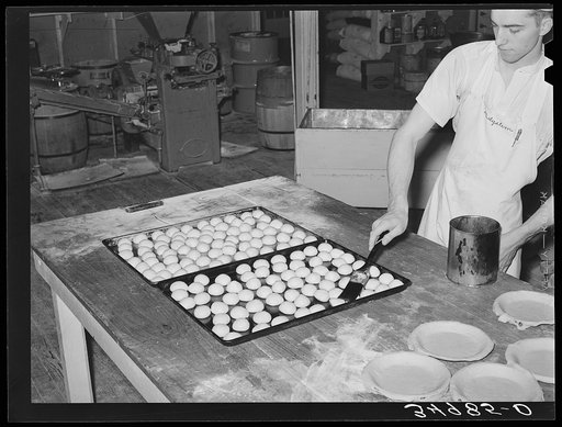 Brushing top of rolls with melted grease so that they will brown. Bakery, San Angelo, Texas