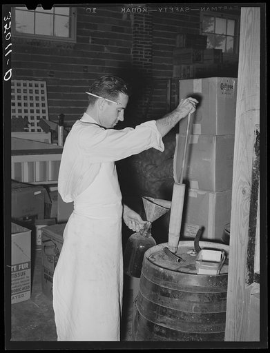 Clerk at grocery store filling bottle with vinegar. San Angelo, Texas