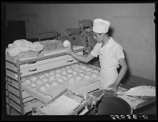 Throwing balls of dough onto rack where they will be shaped into loaves, allowed to rise, and then baked. Bakery, San Angelo, Texas