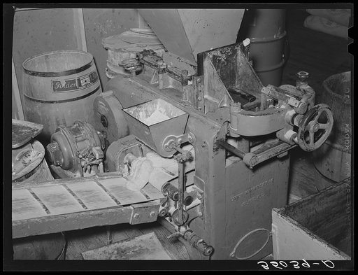 Machine which automatically weighs and delivers dough for making loaves of bread. Bakery, San Angelo, Texas